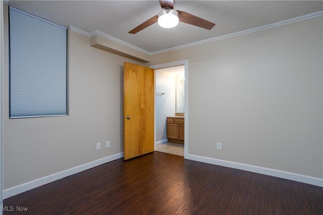 empty room with ceiling fan, crown molding, dark wood-style floors, and baseboards