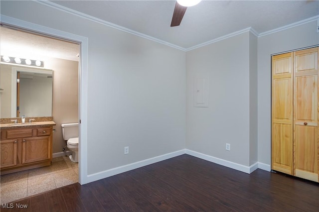 unfurnished bedroom with sink, dark hardwood / wood-style flooring, ceiling fan, crown molding, and ensuite bath