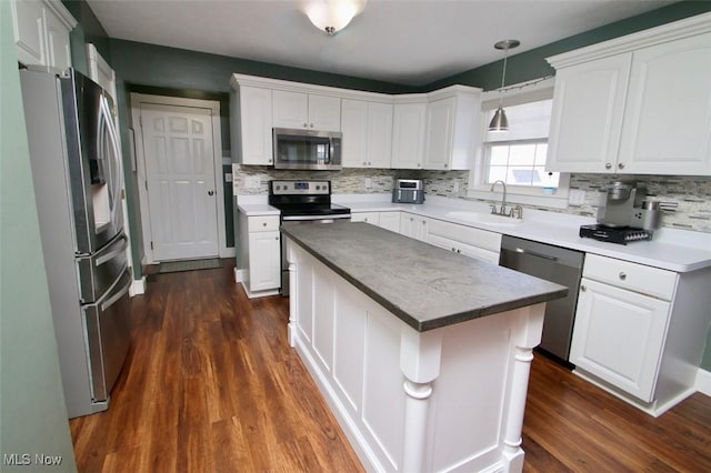 kitchen featuring appliances with stainless steel finishes, pendant lighting, white cabinetry, sink, and a center island