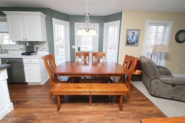 dining room with dark wood-type flooring, a chandelier, sink, and a wealth of natural light