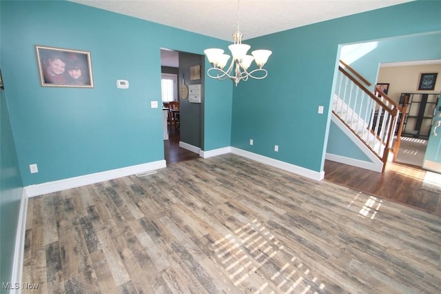 unfurnished room with hardwood / wood-style flooring and a notable chandelier