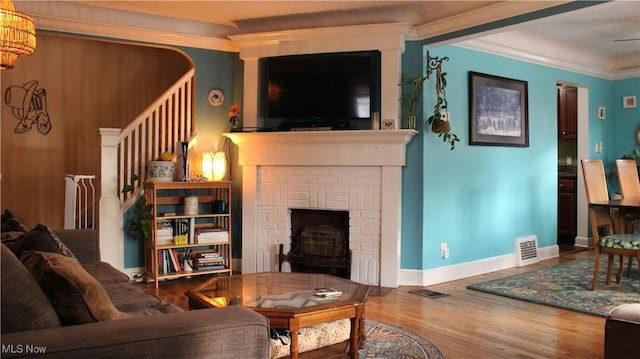 living room with ornamental molding, a fireplace, and hardwood / wood-style floors