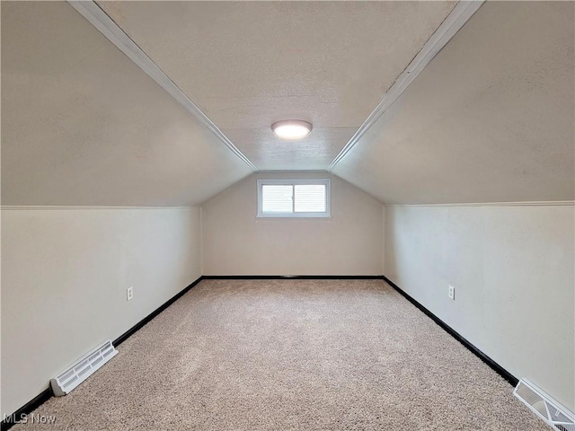 bonus room with carpet flooring, vaulted ceiling, and a textured ceiling