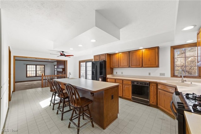 34210 Beacon Dr, Willoughby, OH 44094 - kitchen featuring sink, a kitchen island, black appliances, and a kitchen bar