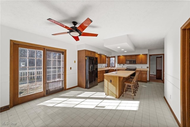 34210 Beacon Dr, Willoughby, OH 44094 - kitchen featuring a kitchen bar, a center island, ceiling fan, black appliances, and a textured ceiling
