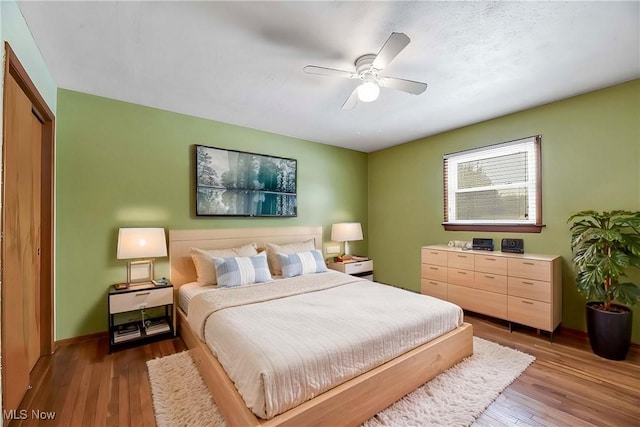 bedroom with dark wood-type flooring, ceiling fan, and a closet