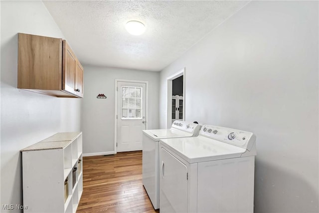 laundry area featuring washer and clothes dryer, cabinets, a textured ceiling, and light wood-type flooring