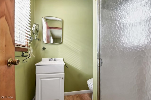 bathroom featuring tile patterned flooring, vanity, a shower with door, and toilet