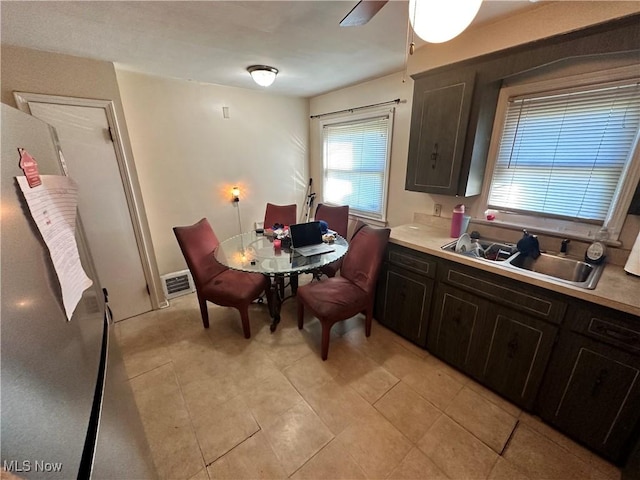 tiled dining space with ceiling fan and sink