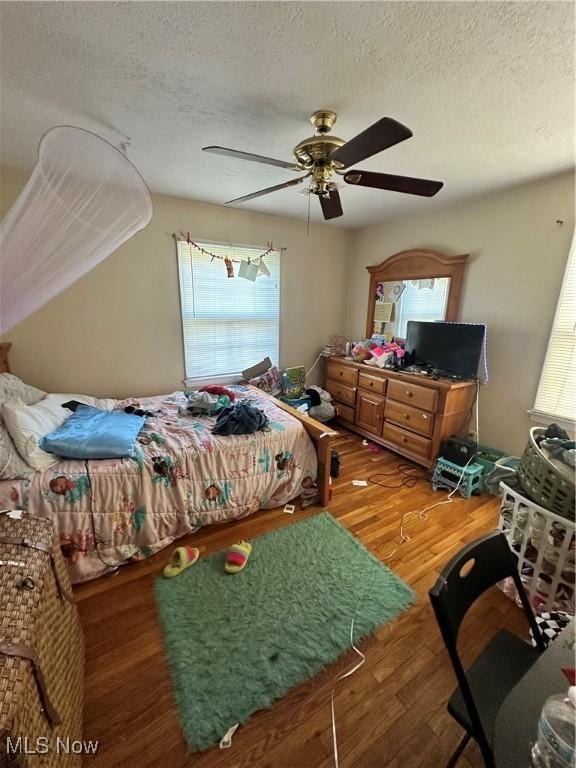 bedroom featuring ceiling fan, wood-type flooring, and a textured ceiling