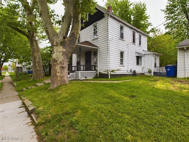 rear view of house featuring a yard and covered porch