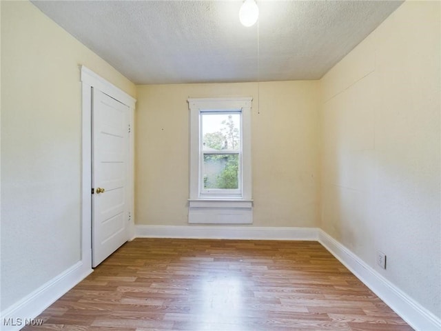 unfurnished room featuring light hardwood / wood-style flooring and a textured ceiling