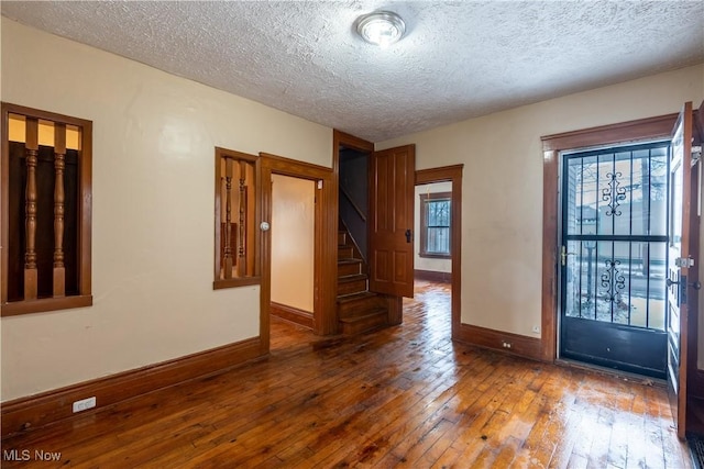 unfurnished room featuring dark wood-type flooring and a textured ceiling