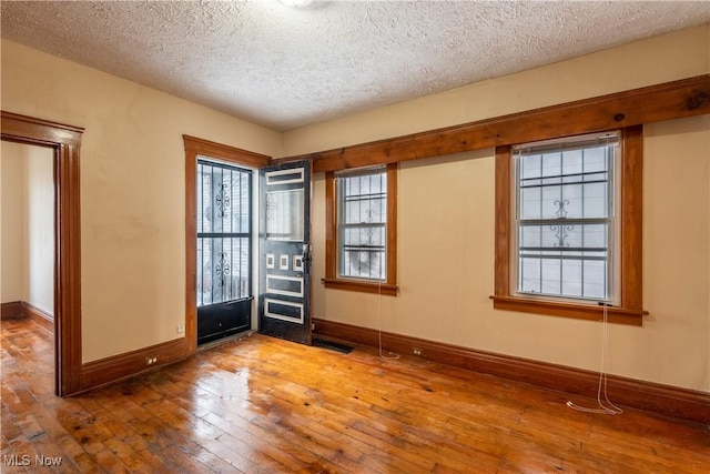 unfurnished room with hardwood / wood-style flooring and a textured ceiling