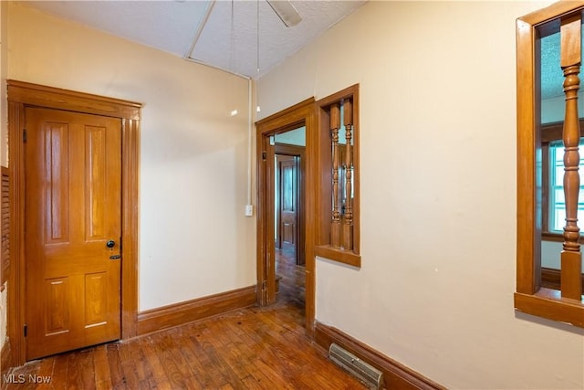 corridor with wood-type flooring, a textured ceiling, and vaulted ceiling