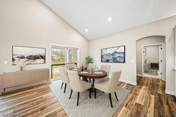 dining space with hardwood / wood-style flooring and high vaulted ceiling