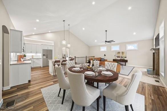 dining room with ceiling fan, high vaulted ceiling, and hardwood / wood-style floors