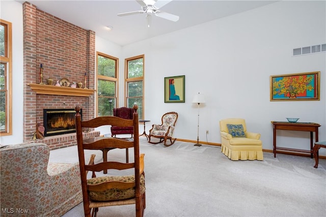 living room featuring a brick fireplace, ceiling fan, and carpet