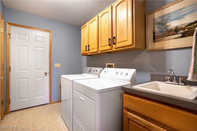 laundry room featuring cabinets, sink, washing machine and dryer, and a textured ceiling