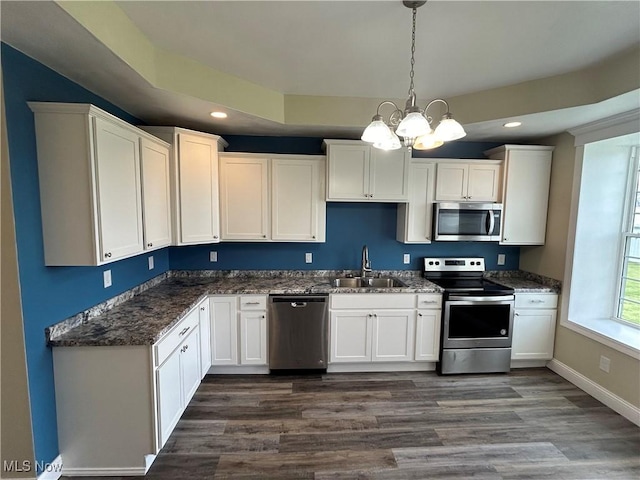 kitchen with appliances with stainless steel finishes, decorative light fixtures, white cabinetry, sink, and dark hardwood / wood-style flooring