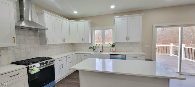 kitchen with wall chimney exhaust hood, sink, white cabinetry, a center island, and stainless steel appliances