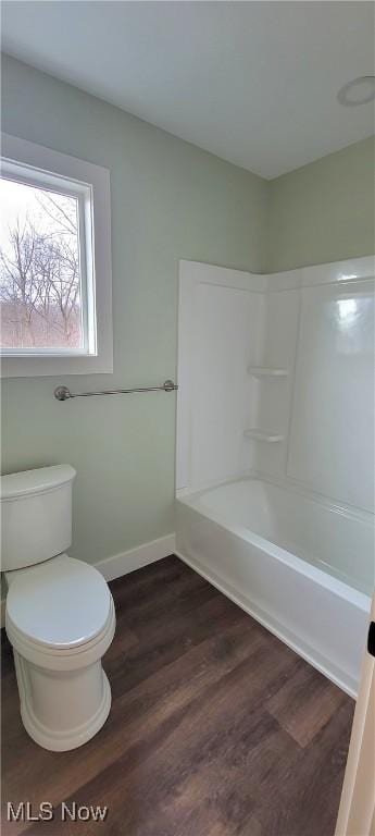 bathroom with hardwood / wood-style flooring, bathtub / shower combination, and toilet