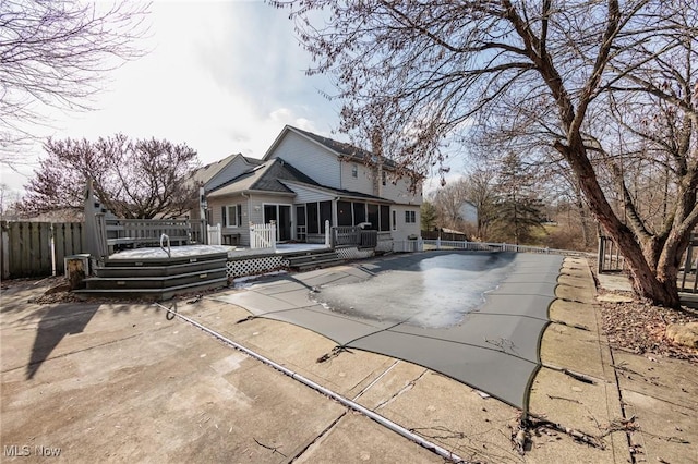 back of property with a wooden deck, a sunroom, and a patio area