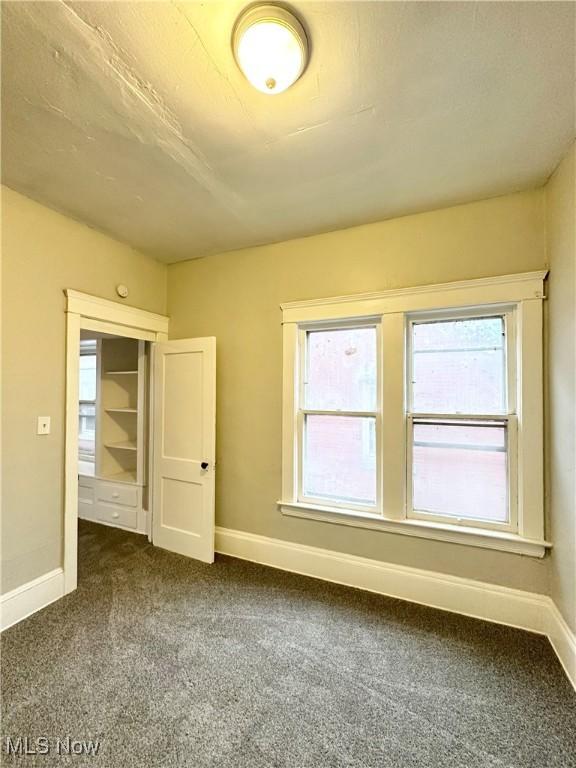 unfurnished bedroom featuring multiple windows and dark colored carpet