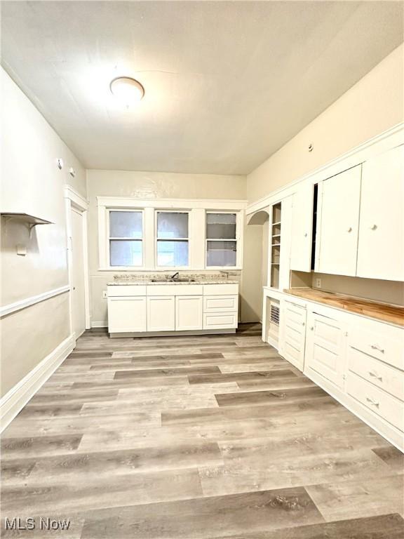 kitchen with white cabinetry, sink, and light wood-type flooring