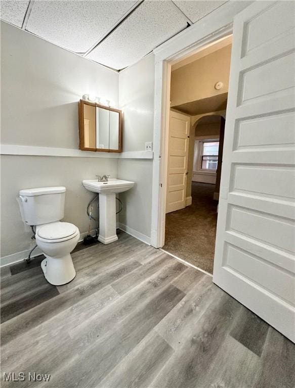 bathroom featuring hardwood / wood-style flooring, toilet, sink, and a drop ceiling