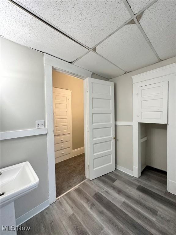 unfurnished bedroom with dark hardwood / wood-style floors, sink, a closet, and a drop ceiling