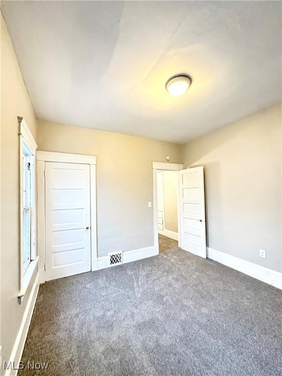 unfurnished bedroom with a closet and dark colored carpet