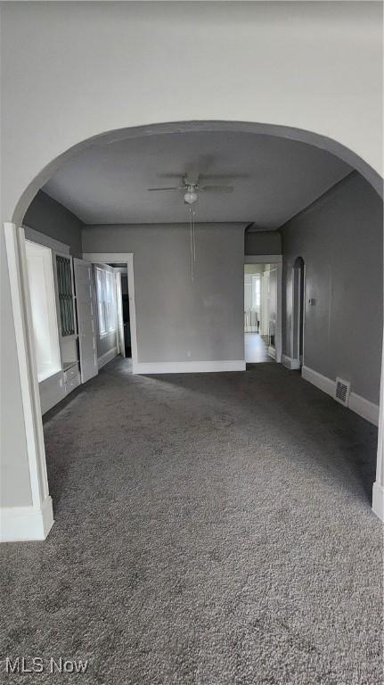 unfurnished living room with ceiling fan and dark carpet