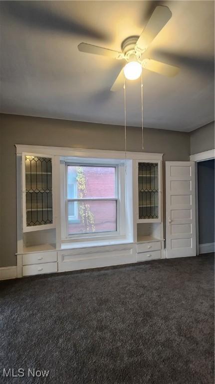 interior space with ceiling fan and dark colored carpet