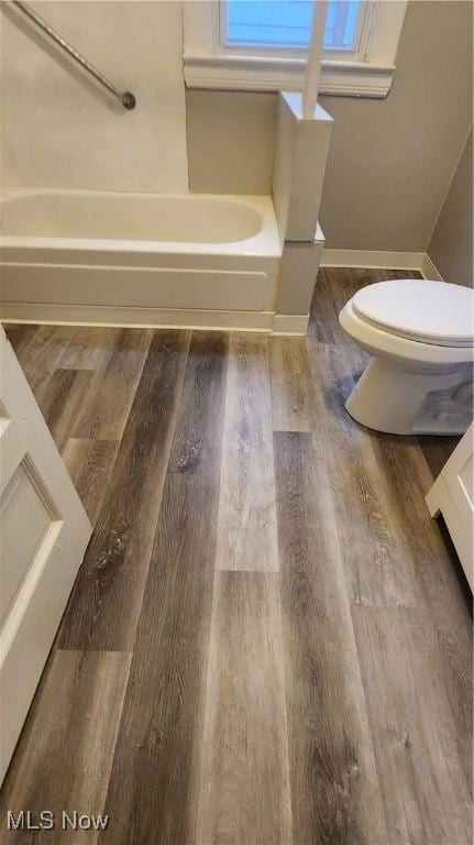 bathroom with hardwood / wood-style flooring, toilet, and a washtub