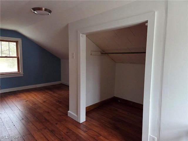 additional living space featuring vaulted ceiling and dark wood-type flooring