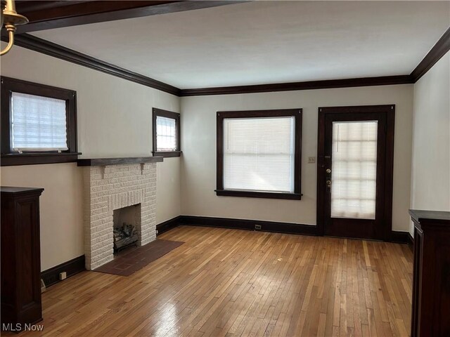 unfurnished living room featuring crown molding, a fireplace, and light hardwood / wood-style floors