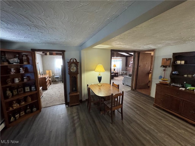 dining space featuring a healthy amount of sunlight, dark hardwood / wood-style flooring, and a textured ceiling