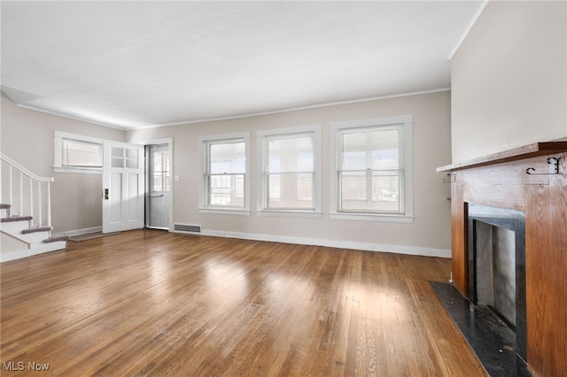 unfurnished living room with wood-type flooring and crown molding