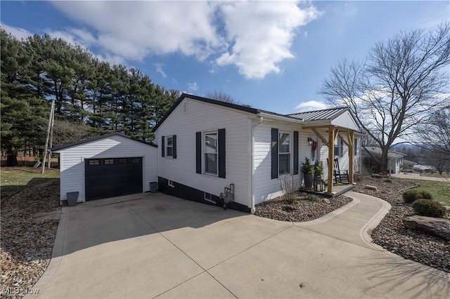 view of side of property featuring a garage, an outdoor structure, and covered porch