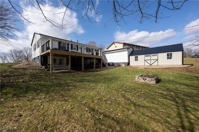 rear view of house featuring a yard, a deck, an outdoor fire pit, and a shed