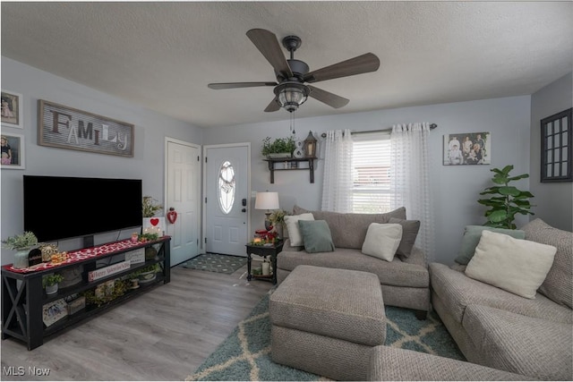 living room with hardwood / wood-style flooring, ceiling fan, and a textured ceiling