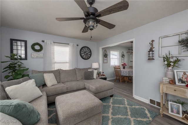 living room featuring ceiling fan, a healthy amount of sunlight, and dark hardwood / wood-style flooring