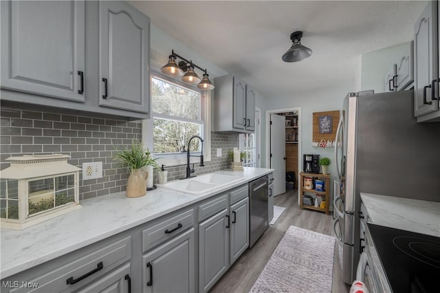 kitchen featuring stainless steel appliances, gray cabinets, sink, and light hardwood / wood-style flooring