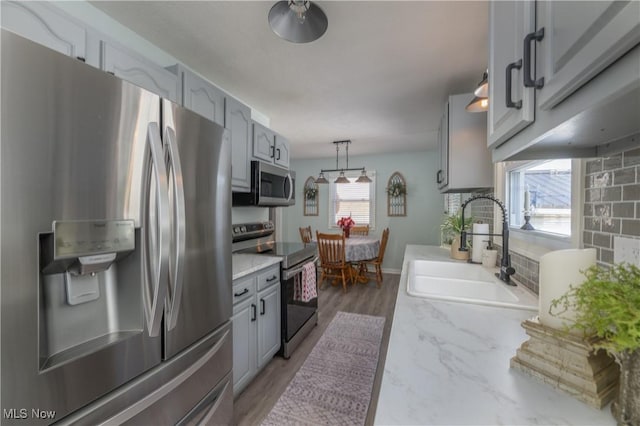 kitchen featuring gray cabinets, sink, hanging light fixtures, stainless steel appliances, and dark wood-type flooring