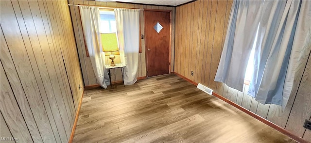 entryway featuring light wood-type flooring and wood walls