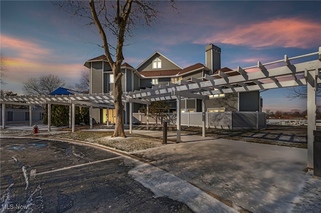 back house at dusk featuring a pergola