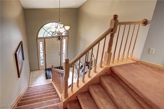 entrance foyer featuring light tile patterned flooring, a towering ceiling, and a notable chandelier