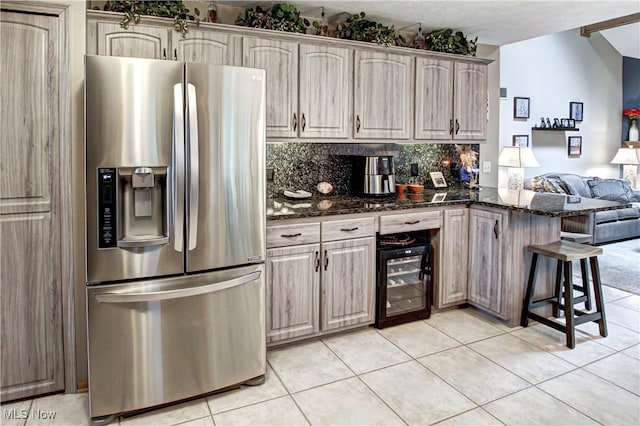 kitchen with stainless steel fridge, a kitchen bar, decorative backsplash, dark stone counters, and kitchen peninsula