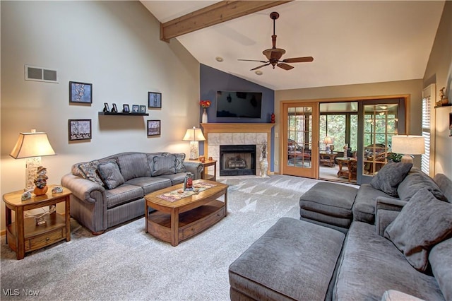 living room with high vaulted ceiling, beamed ceiling, carpet floors, a tiled fireplace, and ceiling fan